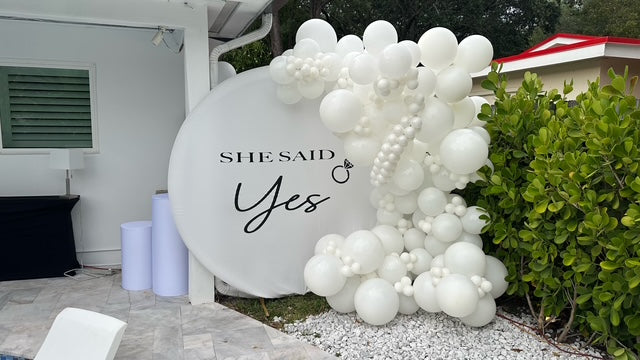 Decorative balloon arch with 'SHE SAID Yes' sign outdoors.