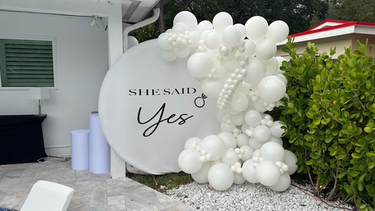 Decorative balloon arch with 'SHE SAID Yes' sign outdoors.